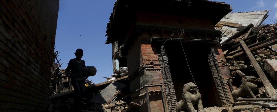 Boy carrying a bolster walks past a damaged temple after Saturday's earthquake in Bhaktapur, Nepal